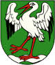 Grafika przedstawia herb gminy Kawęczyn. Zdjęcie bociana przygotowującego się do lotu na zielonym tle